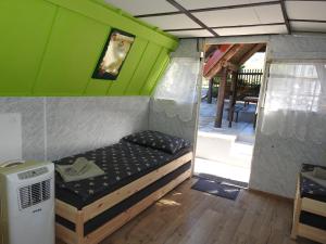 a small bed in a tiny house with a porch at Ubytovanie u Krokodíla in Banská Belá