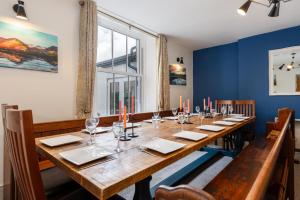 a long wooden table in a room with a large window at The Tall House - Sleeps 16 in Keswick