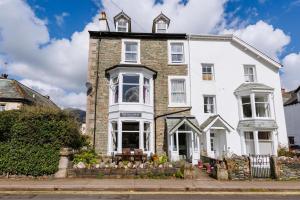 a large white house with a fence in front of it at The Tall House - Sleeps 16 in Keswick