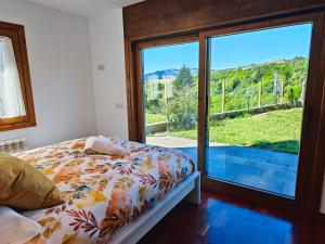 sypialnia z łóżkiem i dużymi przesuwnymi szklanymi drzwiami w obiekcie L'Oasi de Molló w mieście Molló