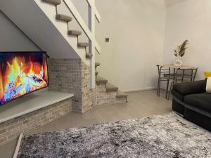 a living room with a tv on a brick fireplace at The Cozy Modern Eastlea Home in Garston
