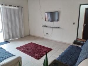 sala de estar con alfombra roja y TV en la pared en Pousada Alvinópolis en Atibaia