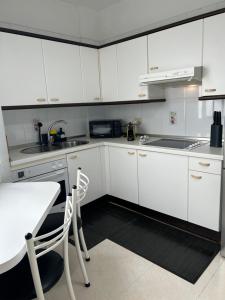 Una cocina con gabinetes blancos y una mesa y sillas. en DREAM BEJIA, en La Laguna