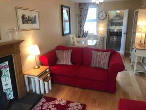 uma sala de estar com um sofá vermelho e uma cozinha em Downshire Cottage: Cosy home in Holywood Centre em Holywood