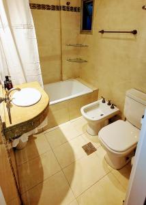 a bathroom with a sink and a toilet and a tub at Avenida Aconquija Suites YB in Yerba Buena