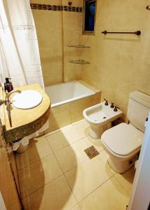 a bathroom with a sink and a toilet and a tub at Avenida Aconquija Suites in Yerba Buena