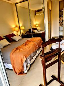 sypialnia z łóżkiem, lustrem i krzesłem w obiekcie Avenida Aconquija Suites YB w mieście Yerba Buena