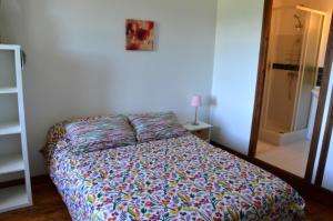 Félines的住宿－Les chambres de Solol，一间卧室配有一张带五颜六色棉被的床