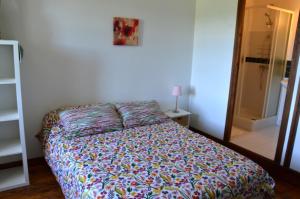 1 dormitorio con 1 cama con un edredón colorido en Les chambres de Solol, en Félines