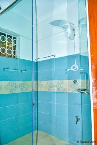eine Glasdusche im Bad mit blauen Fliesen in der Unterkunft The Mevrose Resort in Kisii