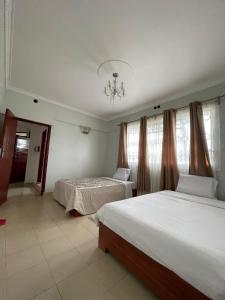 1 dormitorio con 2 camas y lámpara de araña en The Mevrose Resort, en Kisii