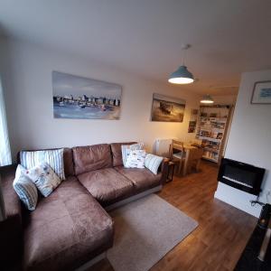 a living room with a brown couch and a television at Hillside in St Austell