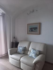 uma sala de estar com um sofá branco com duas almofadas em I Due Camini em Baraggia di Boca