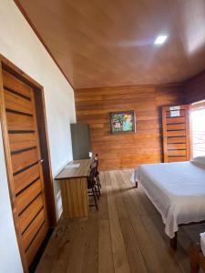 Schlafzimmer mit einem Bett, einem Tisch und einem Schreibtisch in der Unterkunft Pousada Mãe Dita 