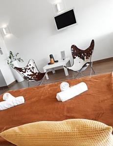 a bedroom with a bed with chairs and a tv at Les Suites du Saint Nazaire - Les Balcons de la Cité in Carcassonne