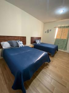 a bedroom with two beds with blue sheets at La Rivera 2 departamentos 