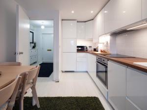 eine Küche mit weißen Schränken und einem Holztisch in der Unterkunft Luxury Haven with King Suites and Parking in London