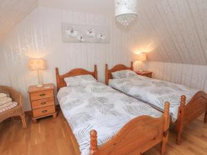 een slaapkamer met 2 bedden en een stoel en een lamp bij Corncrake Cottage SU in Pollachar