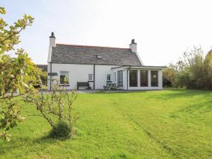 a white house with a large grass yard at Corncrake Cottage SU in Pollachar