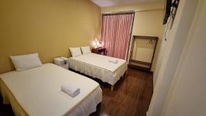 ティンゴ・マリアにあるLEMBRANÇAS HOTEL LODGEのベッド2台と鏡が備わるホテルルームです。