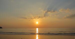 a sunset on the beach with the sun in the sky at Kokotel Khao Lak Lighthouse in Khao Lak