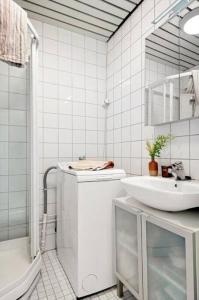 La salle de bains blanche est pourvue d'un lavabo et d'une douche. dans l'établissement Praktisk 1-Roms leilighet, à Oslo