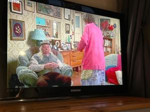 einen TV-Bildschirm mit einer Frau im Wohnzimmer in der Unterkunft A Home from Home in Redditch near town centre in Redditch