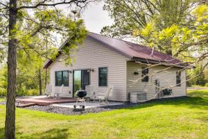 a small white house with a patio and a grill at Pet-Friendly Iron River Cabin with Fire Pit! in Iron River