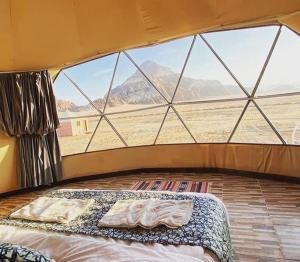 a bed in a tent with a view of the desert at Wadi Rum Calma camp in Aqaba