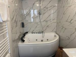 a white bath tub in a bathroom with marble walls at L’escapade Balnéo, Centre ville in Sens