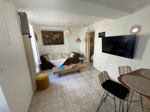 a living room with a couch and a flat screen tv at L’escapade Balnéo, Centre ville in Sens