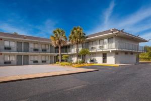 a building with palm trees in front of a street at HomeTowne Studios by Red Roof Orange, TX in Orange