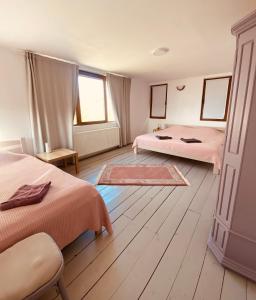 a bedroom with two beds with pink sheets and wooden floors at Cabana Chilii in Cîmpulung