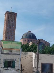 a building with a cross on top of it with two tall buildings at HOSTEL CAMINHO DA FE in Aparecida