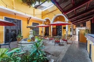 un patio esterno con tavoli, sedie e ombrelloni di Hotel Santiago a Mérida