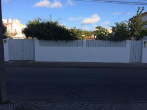 a white fence on a street next to a road at Caparica Holidays in Charneca