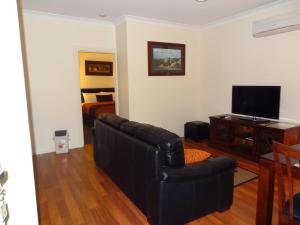 a living room with a couch and a bed at Hahndorf Oak Tree Cottages in Hahndorf