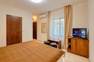 um quarto de hotel com uma cama e uma televisão de ecrã plano em Къща за гости Relax em Hisarja