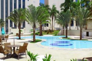 uma piscina com palmeiras, uma mesa e cadeiras em Flat dentro Parque do Peão de Barretos em Barretos