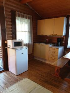 cocina con nevera blanca y microondas en Pahkalanniemi Camping en Parkano