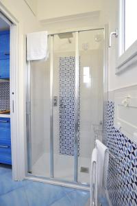 een glazen douche in een badkamer met blauwe tegels bij CASETTAZZURRA in Amalfi