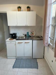 a small kitchen with white cabinets and a sink at Patio de la pietonne in Menton