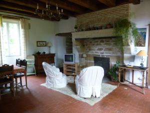a living room with white chairs and a fireplace at Gîte Le Tremblay in Thianges
