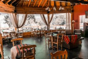 un restaurante con mesas, sillas y ventanas en Complejo Puerto Malén Club de Montaña en Villa Pehuenia