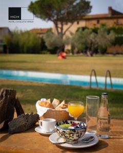 Hotel Canaleta Heras في Espolla: طاولة مع وعاء من الخبز وكوب من عصير البرتقال