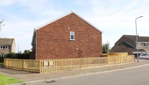 a brick building with a fence next to a street at Modern, Two Double Bedroom House with Free Parking in Chepstow