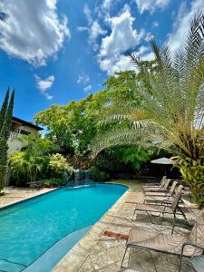 a swimming pool with chairs and palm trees at Hotel Villa Therese in Port-au-Prince
