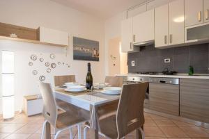 a kitchen with a table with chairs and a bottle of wine at [Burlo Garofalo] Modern Apartment *Wifi+Netflix* in Trieste +11 photos