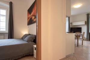 a bedroom with a bed and a kitchen with a table at [Burlo Garofalo] Modern Apartment *Wifi+Netflix* in Trieste