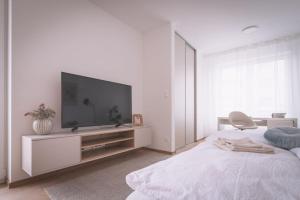 a white bedroom with a flat screen tv on a cabinet at Nový štýlový byt, blízko letiska in Bratislava